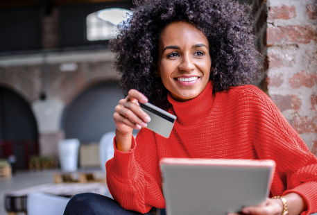 Woman smiling holding credit card and tablet
