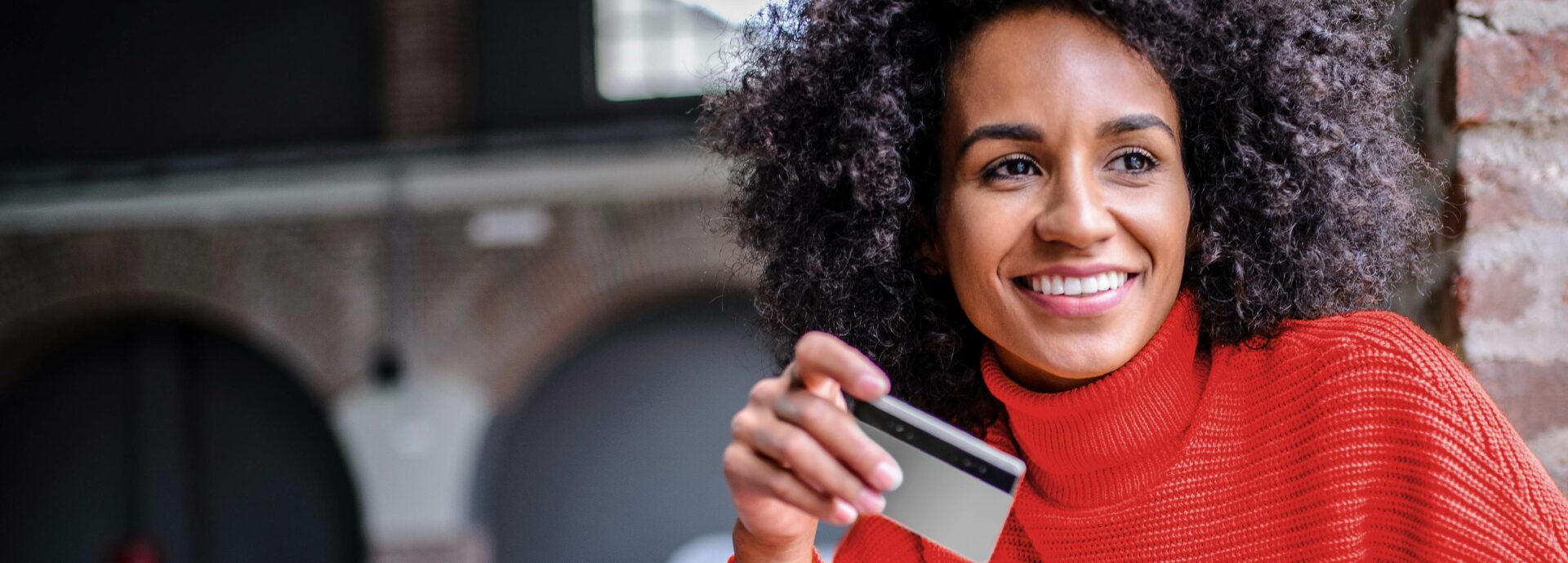 Woman sitting down smiling with credit card and tablet in hand